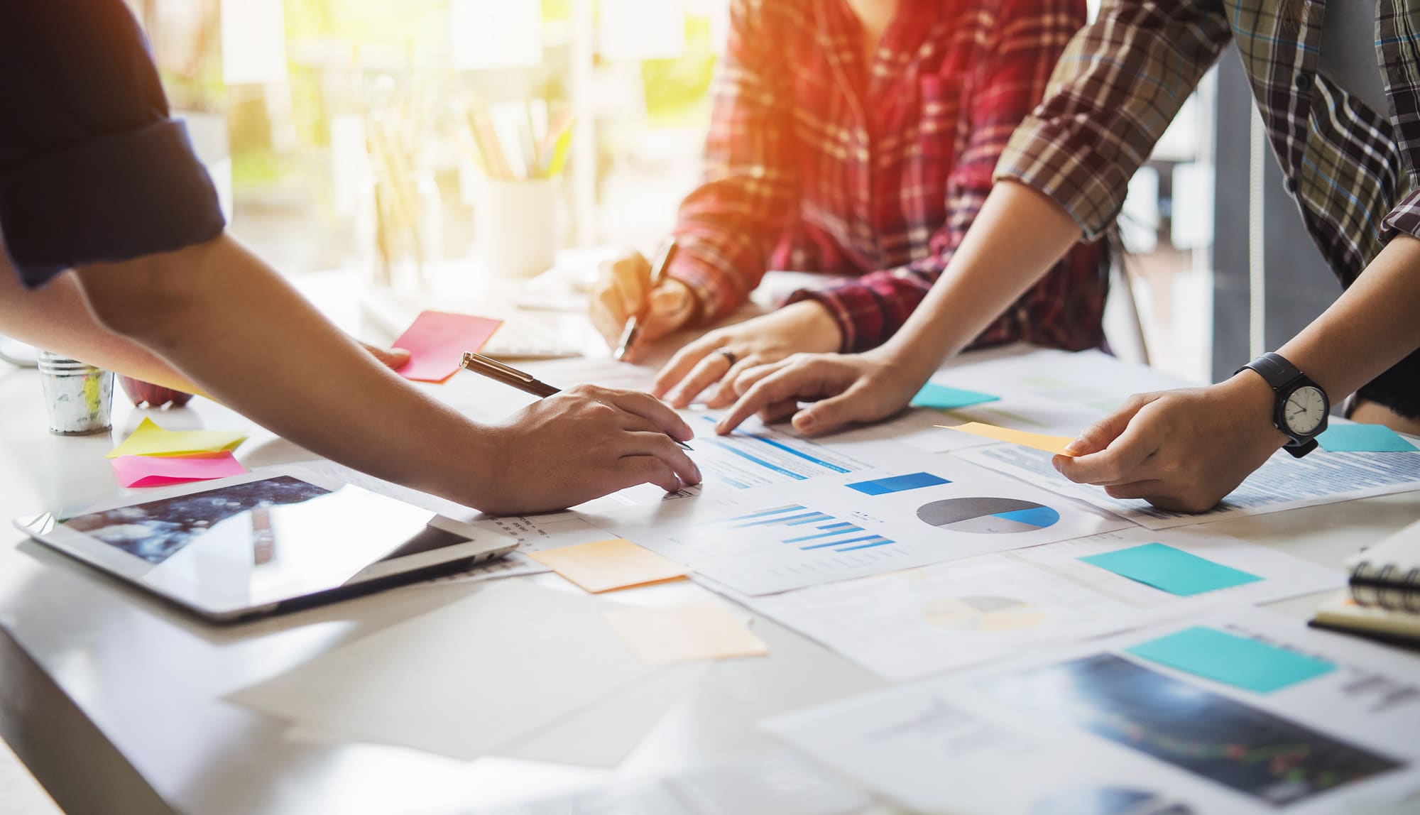 three people gathered around a table with graphs on papers scattered