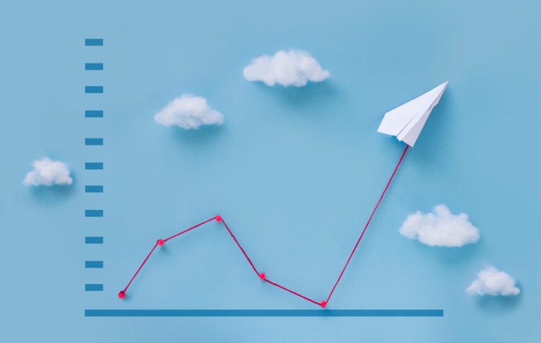 a sales chart with a red line that goes down then back up following a paper airplane